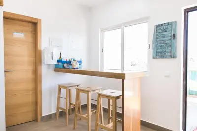 a kitchen with a bar and stools in a room at Good Feeling Hostel & Guest House in Raposeira
