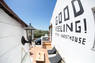 a building with a sign on the side of it at Good Feeling Hostel & Guest House in Raposeira