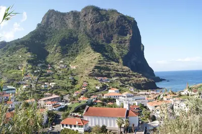 a village on a mountain next to the ocean at Hotel Costa Linda in Porto da Cruz