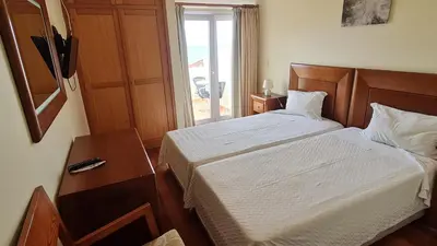 a bedroom with a bed and a table and a window at Hotel Costa Linda in Porto da Cruz