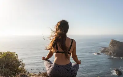 a woman doing yoga on a cliff overlooking the ocean at Hotel Vale Da Telha in Aljezur