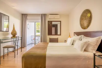 a hotel room with a large bed and a table at Hotel Vale Da Telha in Aljezur