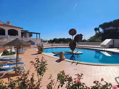 a pool with chairs and umbrellas next to a resort at Apartamentos Salema Praia Club in Salema