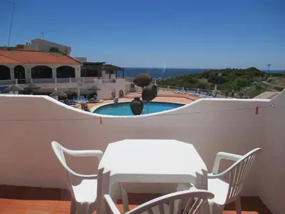 a white table and chairs on a balcony with a pool at Apartamentos Salema Praia Club in Salema