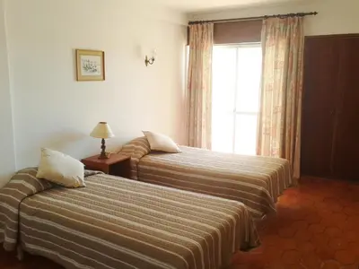 a hotel room with two beds and a window at Apartamentos Salema Praia Club in Salema