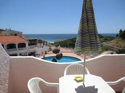 a table and chairs with a view of a pool at Apartamentos Salema Praia Club in Salema