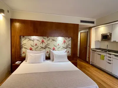 a bedroom with a white bed with a floral wall at Apartamentos Turisticos Atlantida in Funchal