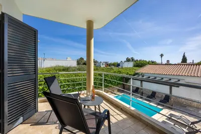 a balcony with a table and chairs and a swimming pool at Montinhos Nature Stay in Luz