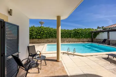 a swimming pool in a house with chairs and a patio at Montinhos Nature Stay in Luz