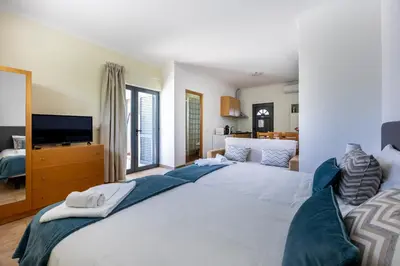 a large white bed in a bedroom with a television at Montinhos Nature Stay in Luz