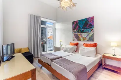 a bedroom with a bed and a desk and a tv at Casa da Ribeira in Funchal