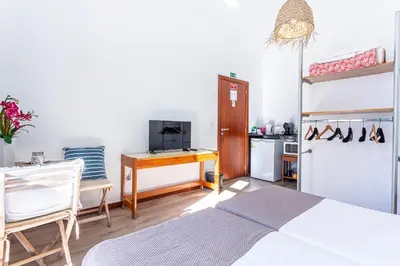 a bedroom with a bed and a desk and a kitchen at Casa da Ribeira in Funchal