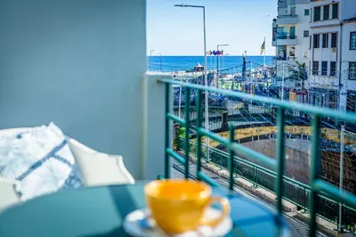 a cup of coffee on a table on a balcony with the ocean at Casa da Ribeira in Funchal