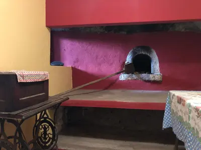 a room with a red wall with a pizza oven at Casa da Igreja in Santana