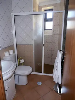 a bathroom with a toilet and a glass shower at Quinta Escola in Arco da Calheta