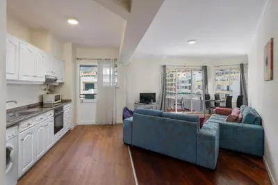 a living room with a blue couch and a kitchen at Golden Star AV by An Island Apart in Funchal