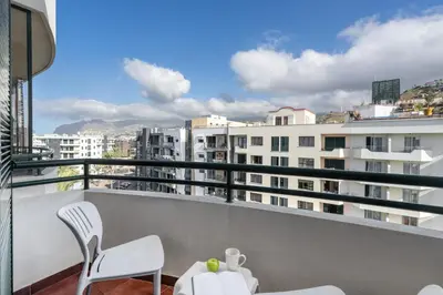 a balcony with white chairs and a view of buildings at Golden Star AV by An Island Apart in Funchal