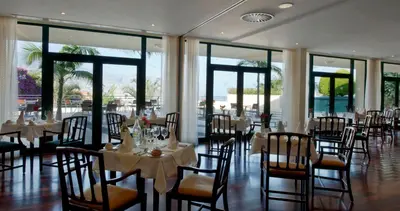 a dining room with tables and chairs and windows at Madeira Panorâmico Hotel in Funchal