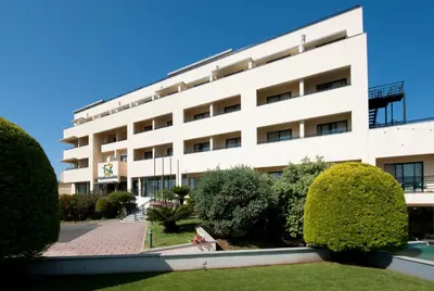 a white building with trees in front of it at Madeira Panorâmico Hotel in Funchal