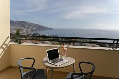 a laptop computer sitting on a table on a balcony at Madeira Panorâmico Hotel in Funchal