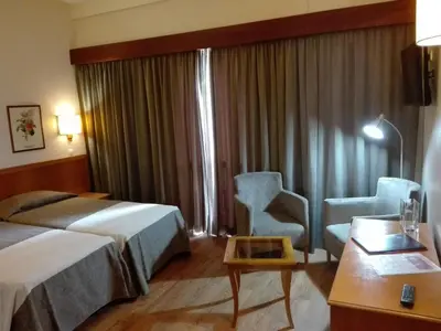 a hotel room with a bed and a chair and a desk at Hotel Do Centro in Funchal