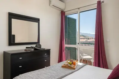 a bedroom with a bed and a dresser and a window at Golden Star AU by An Island Apart in Funchal