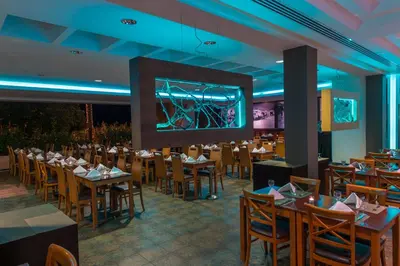 a restaurant with tables and chairs and a large screen at Vila Baleira Porto Santo in Porto Santo