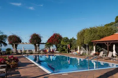 a swimming pool at a resort with chairs and umbrellas at Ocean Gardens in Funchal