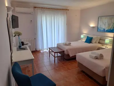 a hotel room with two beds and a chair at Aurora Sol in Luz