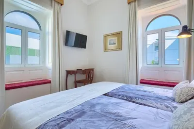 a bedroom with a large bed with two windows at Century House with private pool by Holiday Rental Madeira in Funchal