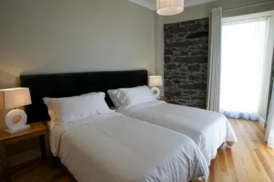 a bedroom with two beds and a brick wall at The Docks in Paul do Mar