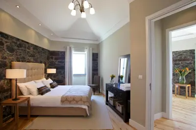 a bedroom with a king sized bed with a stone wall at The Docks in Paul do Mar