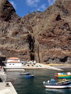 a group of boats in the water next to a mountain at The Docks in Paul do Mar
