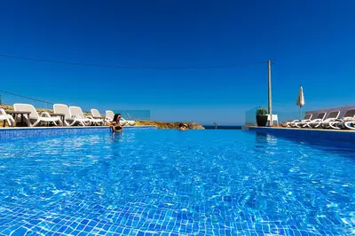 a woman sitting in a swimming pool with chairs at Mareta Beach - Boutique Bed & Breakfast in Sagres