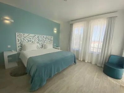 a bedroom with a bed and a blue chair at Mareta Beach - Boutique Bed & Breakfast in Sagres