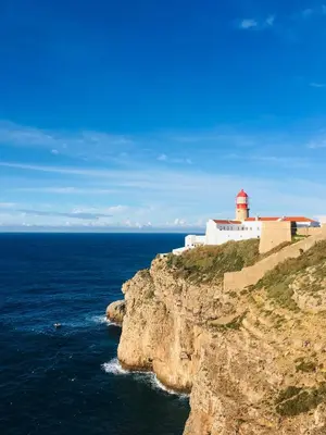 a lighthouse on a cliff next to the ocean at Mareta Beach - Boutique Bed & Breakfast in Sagres