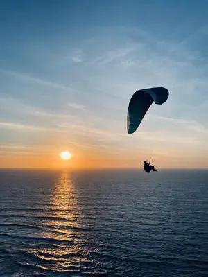 a person is riding a parachute over the ocean at Mareta Beach - Boutique Bed & Breakfast in Sagres