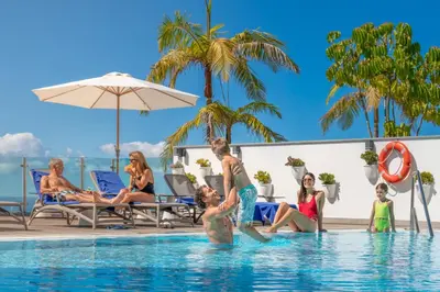a group of people sitting in the swimming pool at a resort at Vila Baleira Funchal in Funchal