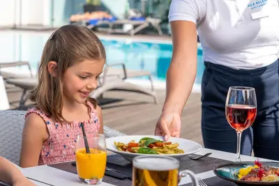 a little girl sitting at a table with a plate of food at Vila Baleira Funchal in Funchal