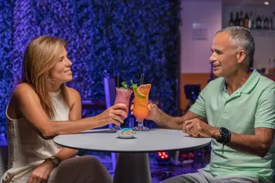 a man and a woman sitting at a table with cocktails at Vila Baleira Funchal in Funchal
