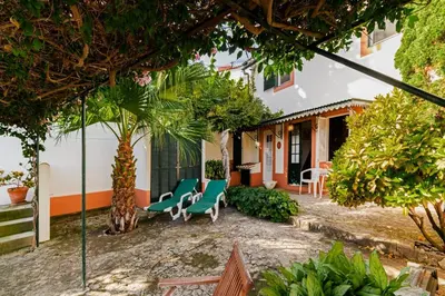 a patio with chairs and trees in front of a house at Quinta Florença - By WeHost in Funchal
