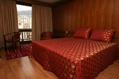 a bedroom with a bed with a red blanket and a window at Hotel Catedral in Funchal