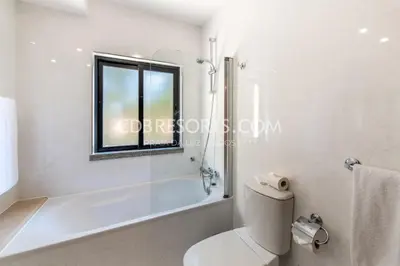 a bathroom with a tub and a toilet and a window at Baia da Luz Resort in Luz