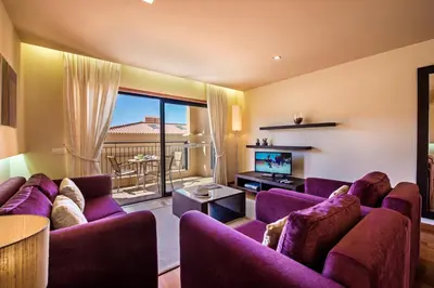 a living room with purple couches and a tv at Baia da Luz Resort in Luz