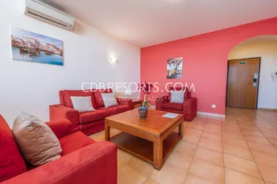 a living room with red couches and a table at Estrela da Luz Resort in Luz