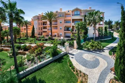 an apartment building with palm trees and a garden at Estrela da Luz Resort in Luz
