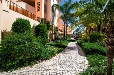 a walkway in front of a building with palm trees at Estrela da Luz Resort in Luz