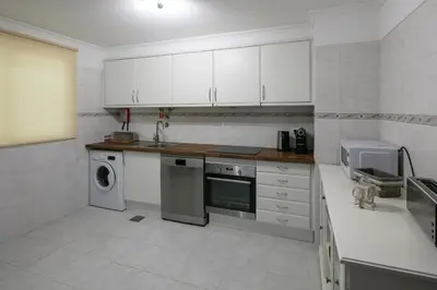 a kitchen with white cabinets and a washer and dryer at Apartment Ocean Gardens in Caniço