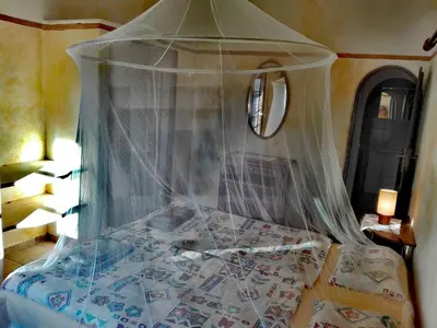 a bedroom with a bed covered in a canopy at Nature Beach Resort Quinta Al-Gharb in Vila do Bispo