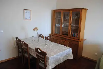 a dining room table with chairs and a wooden cabinet at Pia's Place - Apt with sea view in Caniço